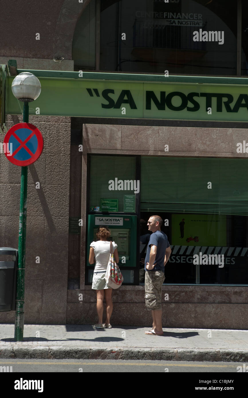 Persone che utilizzano "ATM cash dispenser' 'Sun' nosta banca strada in Palma de Maiorca Spagna Foto Stock