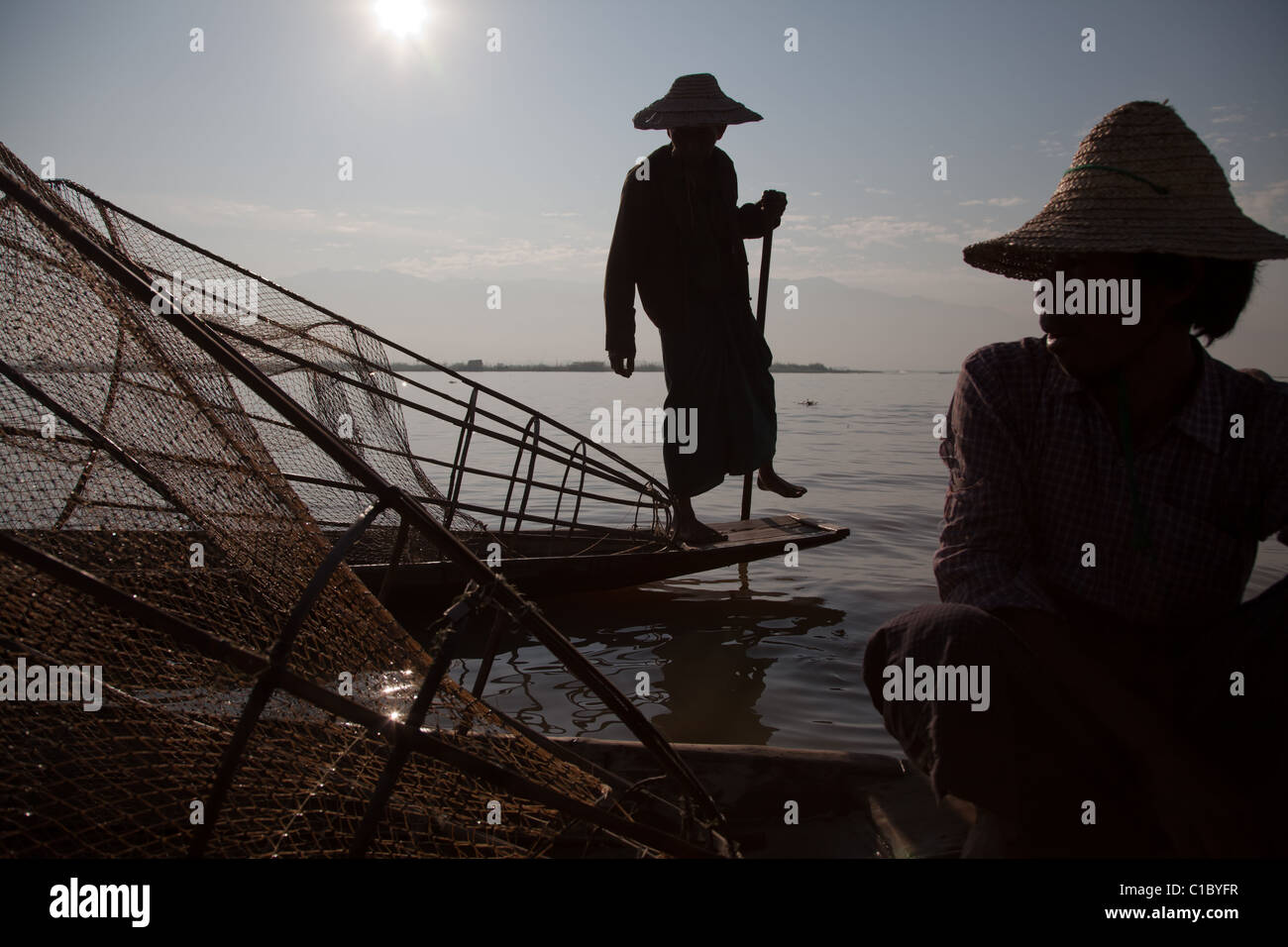 Ammaliante tribal pescatore sul Lago Inle in Birmania. Singolare tecnica di gamba-barca a remi e coniche Tutina in rete. Foto Stock