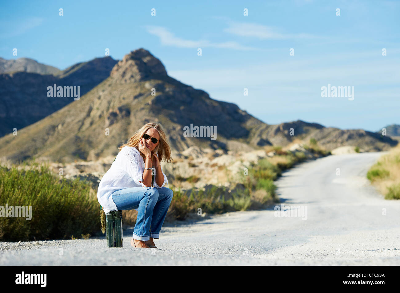 Donna seduta su benzina può in strada Foto Stock