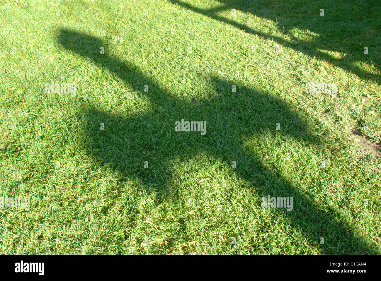 Calda lunga ombra della croce cadere nell'erba verde Foto Stock