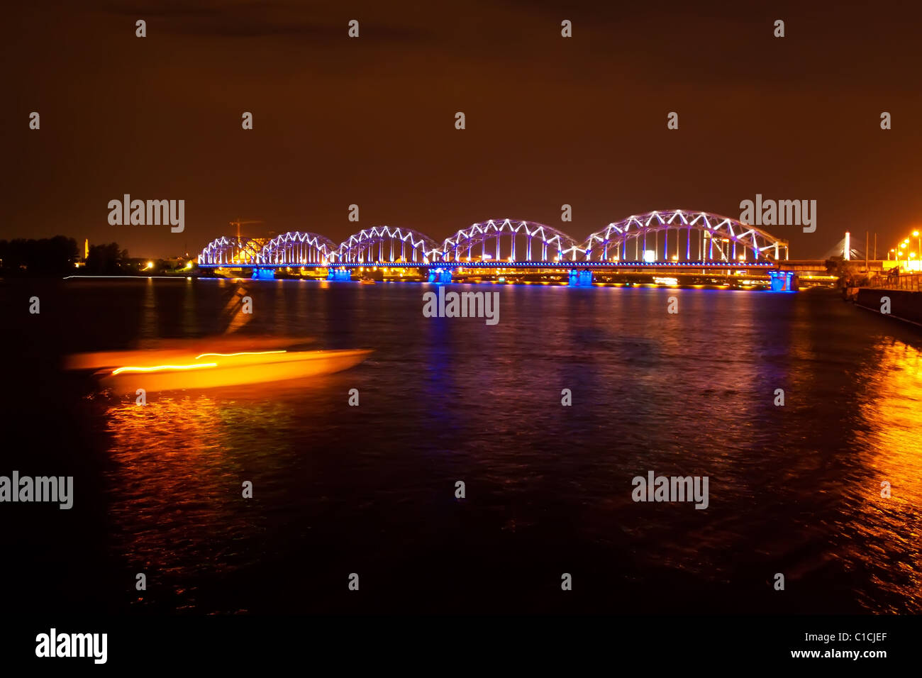 Ponte ferroviario a riga con barca illuminata Foto Stock