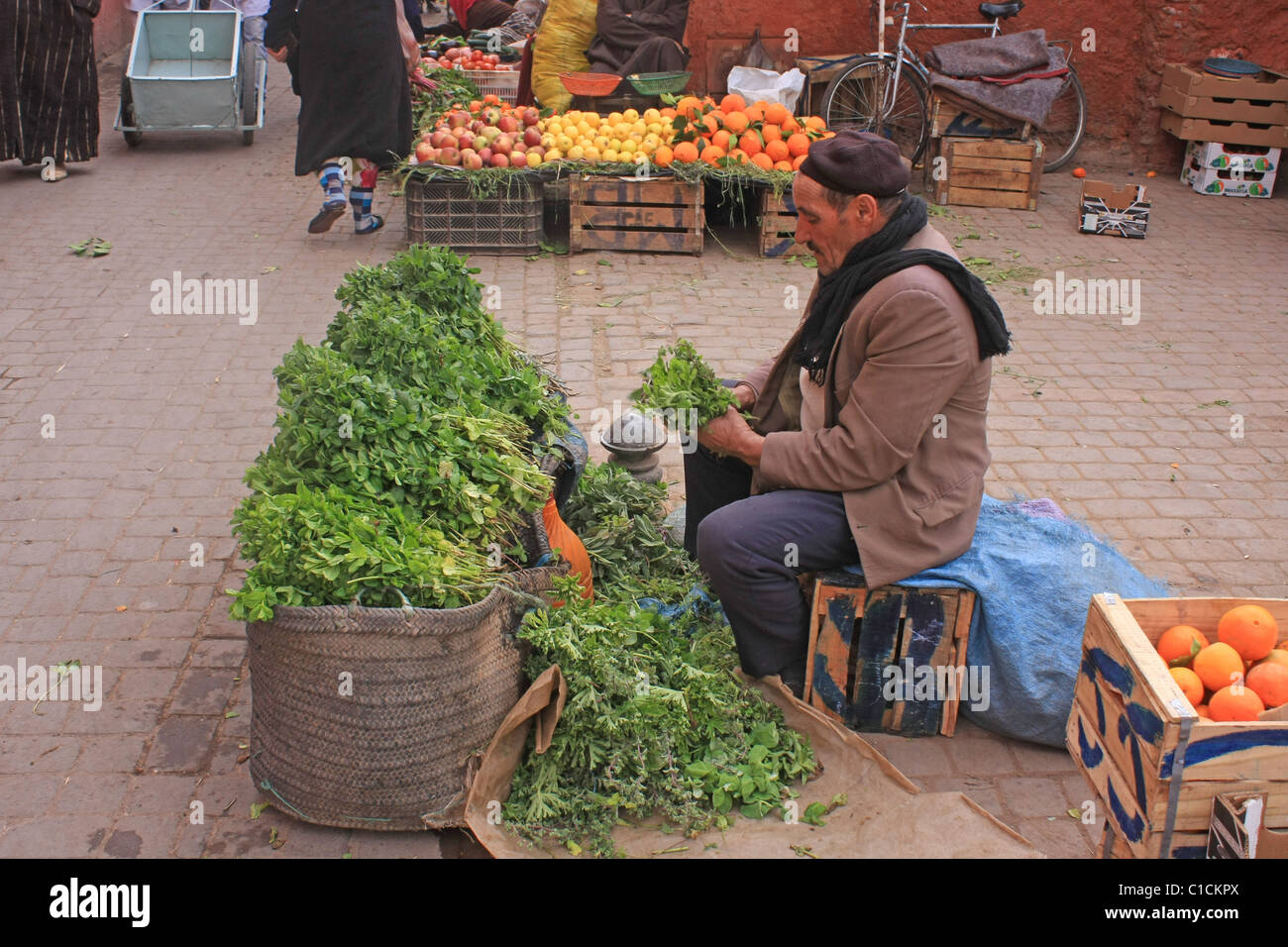 Uomo a preparare verdura in un mercato nel souk di Marrakech Foto Stock