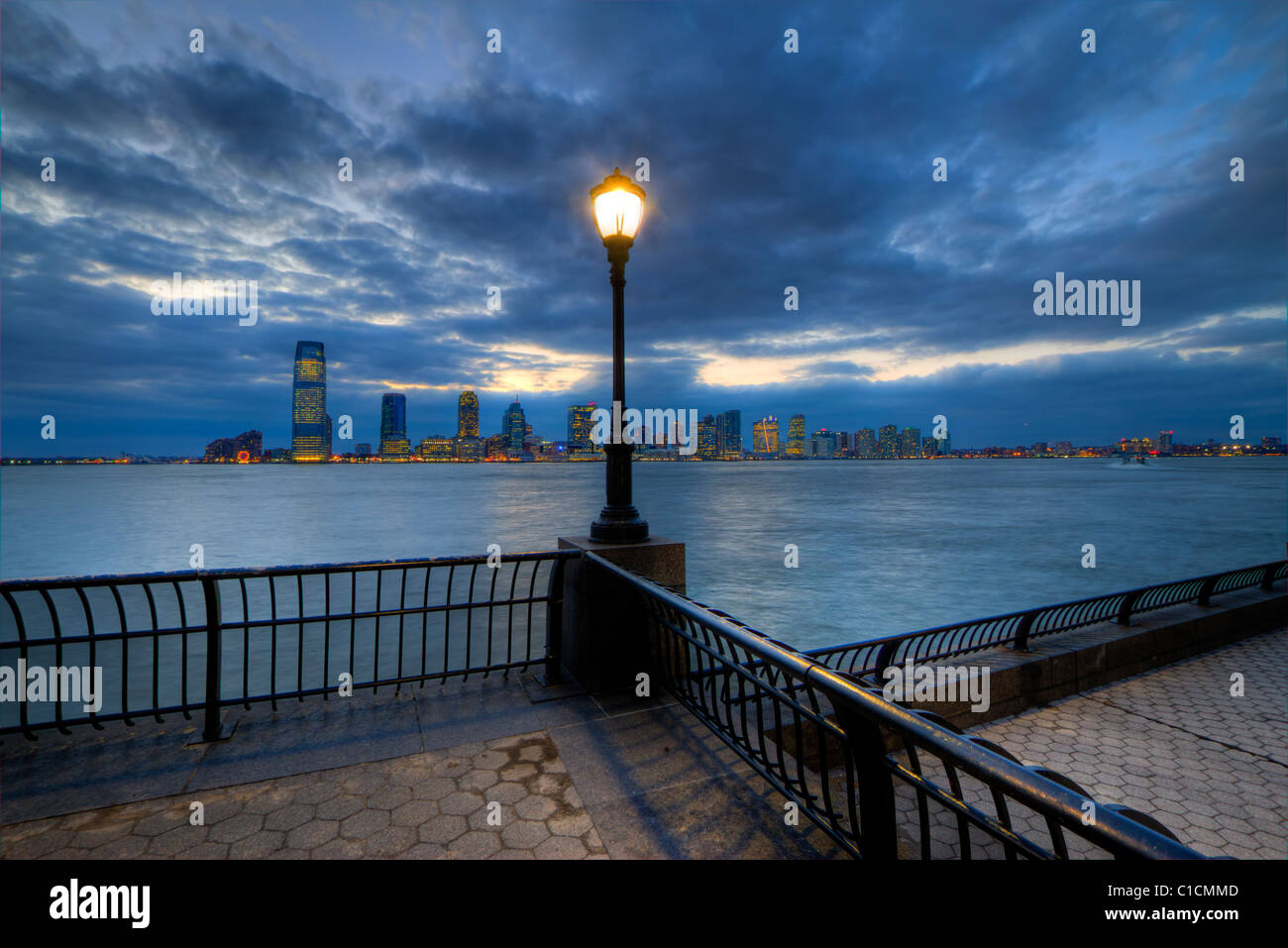 Promenade presso il World Financial Center di bacino in barca a Manhattan di notte con Jersey City visibile sulla sponda opposta Foto Stock
