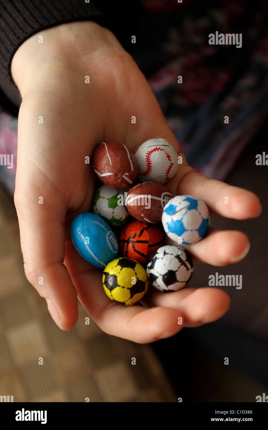 Ragazza con una selezione di dolci al cioccolato avvolto come sport popolari di palline in Brighton, East Sussex, Regno Unito. Foto Stock
