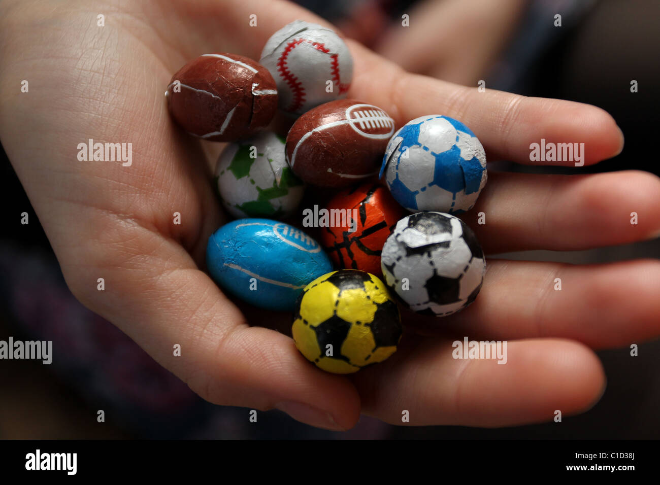 Ragazza con una selezione di dolci al cioccolato avvolto come sport popolari di palline in Brighton, East Sussex, Regno Unito. Foto Stock