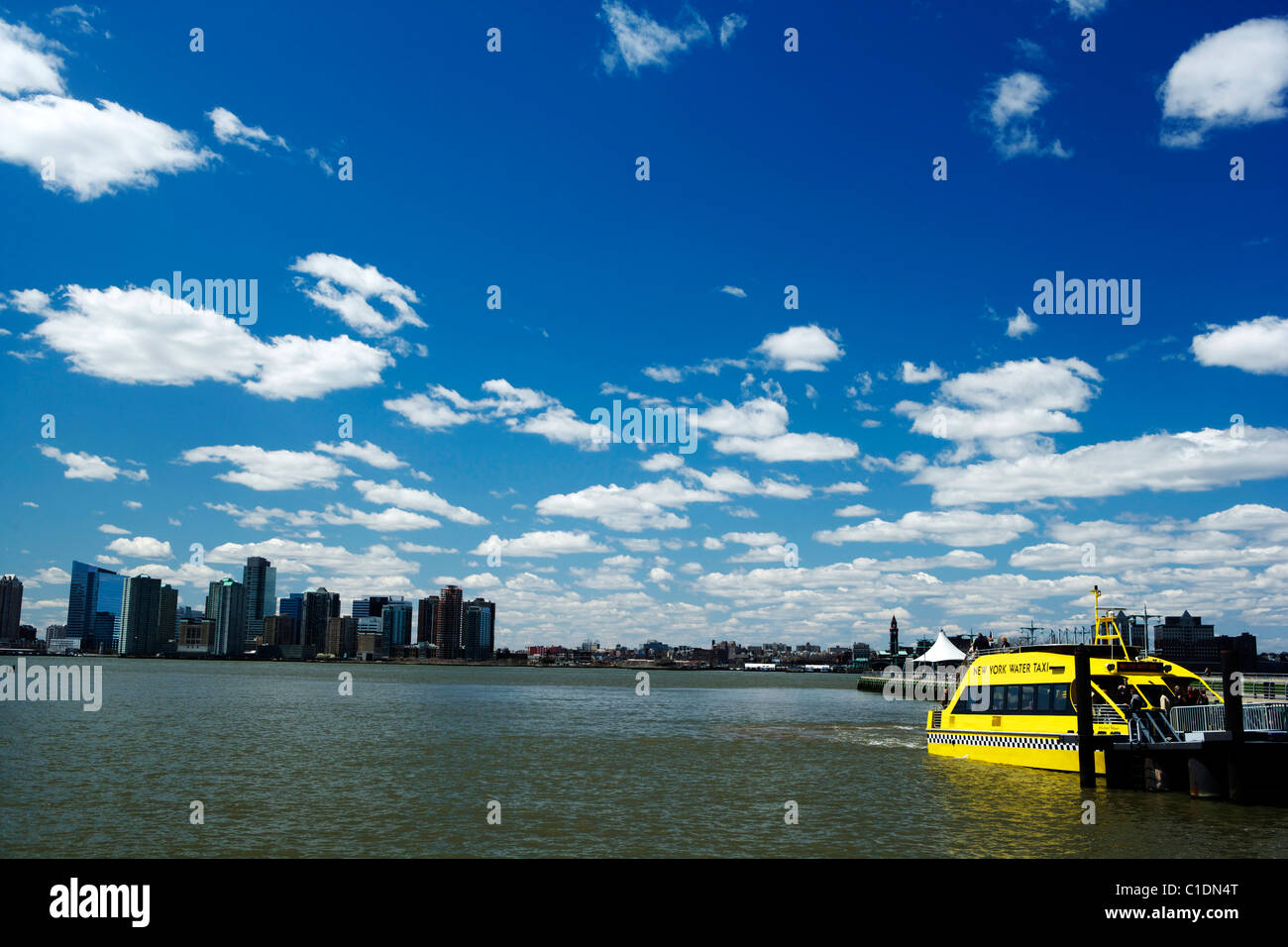 Orizzonte di New York City con un giallo taxi d'acqua sotto un profondo cielo blu con nuvole bianche Foto Stock