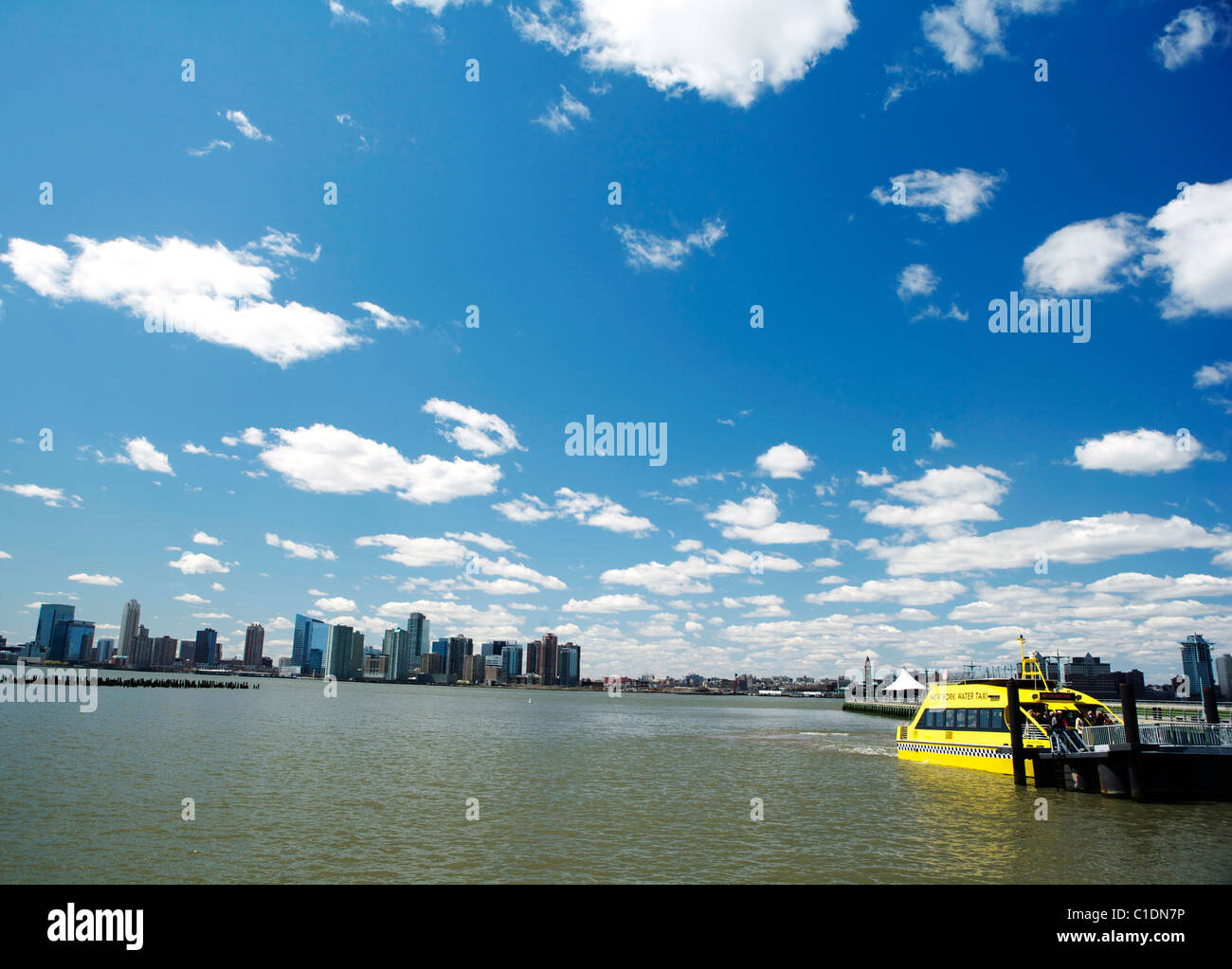 Skyline di New York sotto il cielo blu con un New York giallo taxi d'acqua. Foto Stock