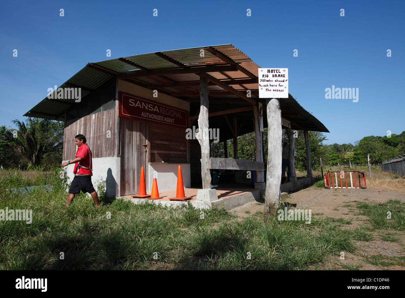 Un uomo cammina fuori del terminal dell'aeroporto edificio nella città isolata di Drake Bay, Osa Peninsula, Costa Rica Foto Stock