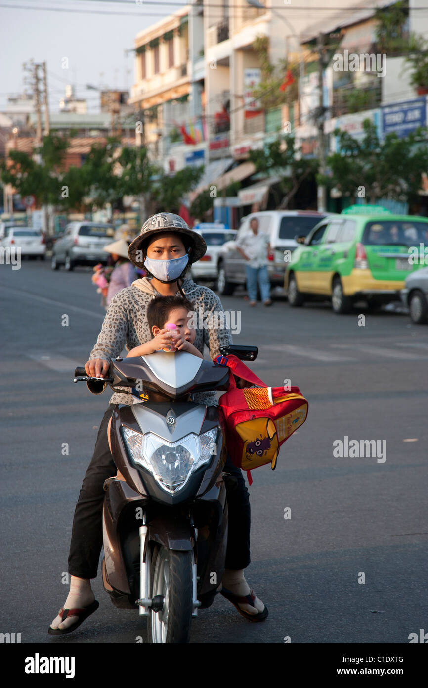 Madre con maschera di inquinamento e il giovane ragazzo senza casco o maschera Foto Stock