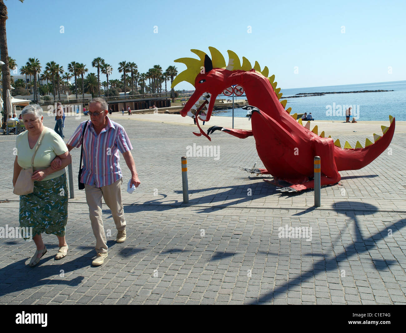 Un modello dragone appare per cacciare una coppia di anziani in Paphos, Cipro. Foto Stock