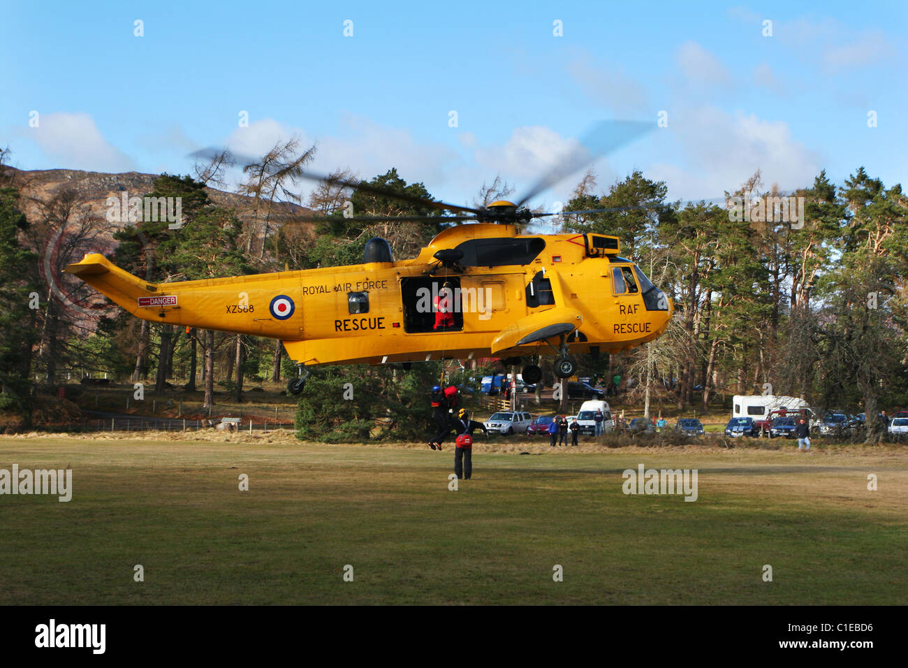 RAF Sea King elicottero SAR hovering e winching un membro di Aviemore Mountain Rescue Team a bordo a Rothiemurchus vicino Aviemor Foto Stock