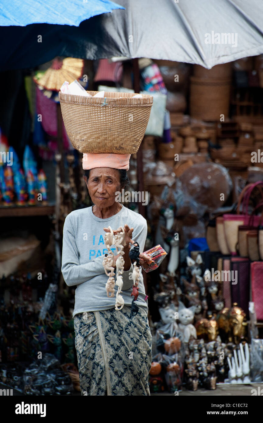 Un gingillo venditore al Ubud Mercato Pubblico di Bali, Indonesia guarda la speranza che una vendita è proprio dietro l'angolo. Foto Stock