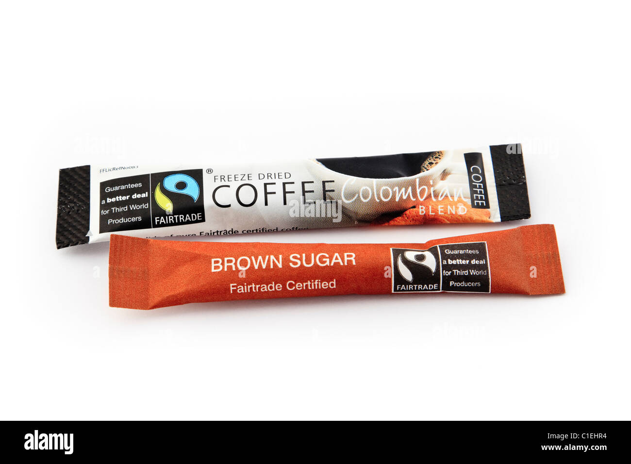 Fairtrade etichette e logo su singole dosi di liofilizzato caffè colombiano e zucchero di canna bustine isolato su uno sfondo bianco. Inghilterra, Regno Unito Foto Stock