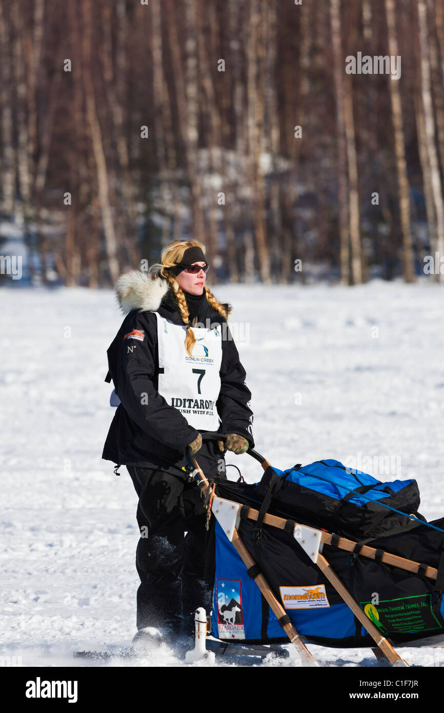 Musher Kristy Berington competere nel trentanovesimo sentiero Iditarod Sled Dog Race sul lungo lago dopo aver lasciato Willow Lago di riavviare. Foto Stock