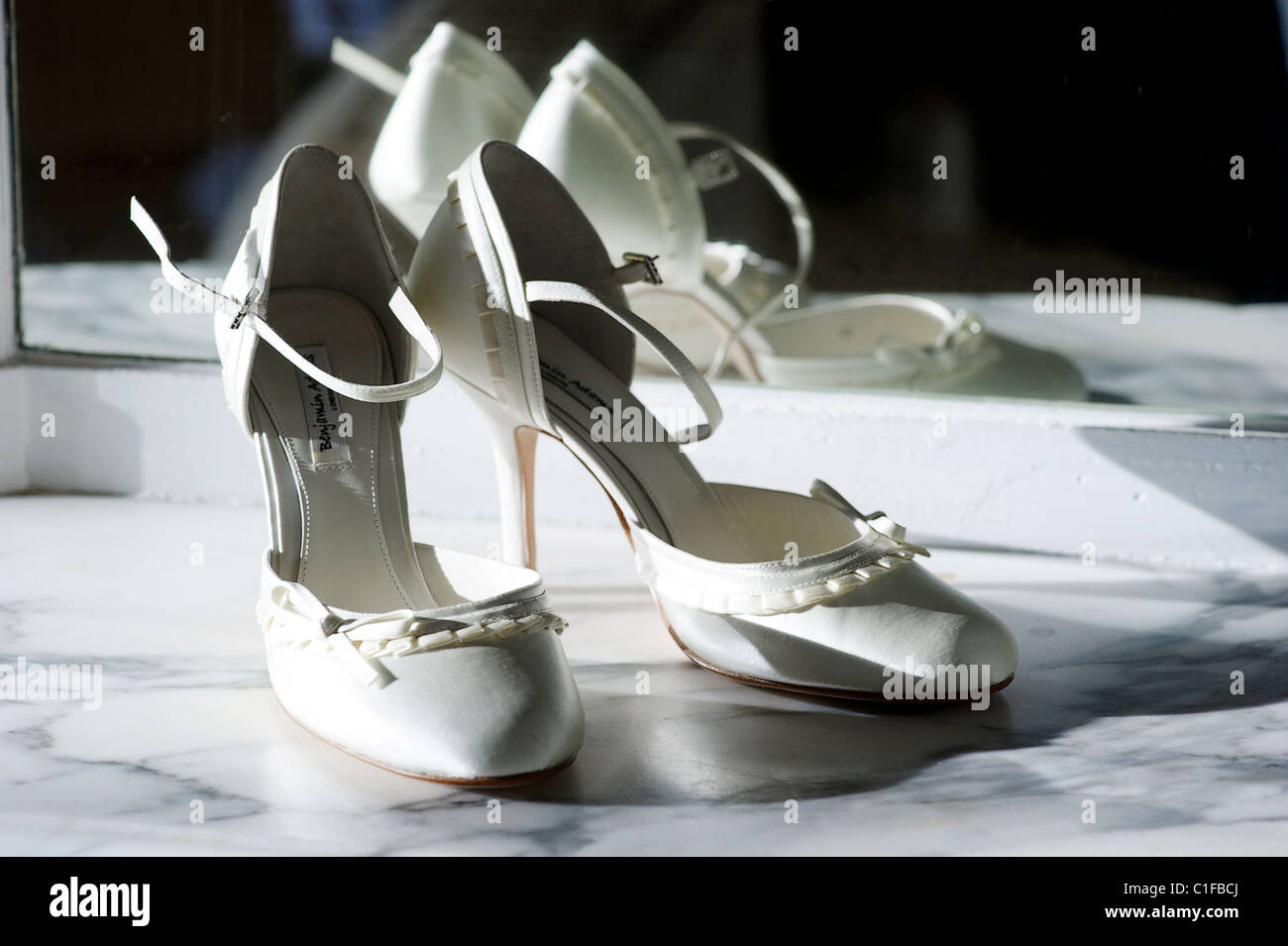Coppia di bianco crema stiletto di nozze scarpe nuziale su un ripiano di marmo contro uno specchio Foto Stock