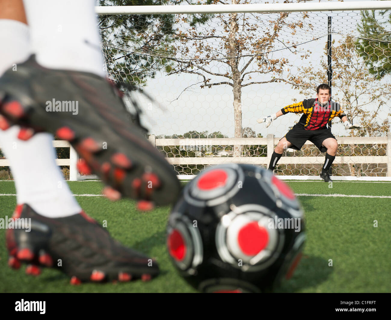 Giocatore di calcio calci palla in obiettivo sul campo di calcio Foto Stock