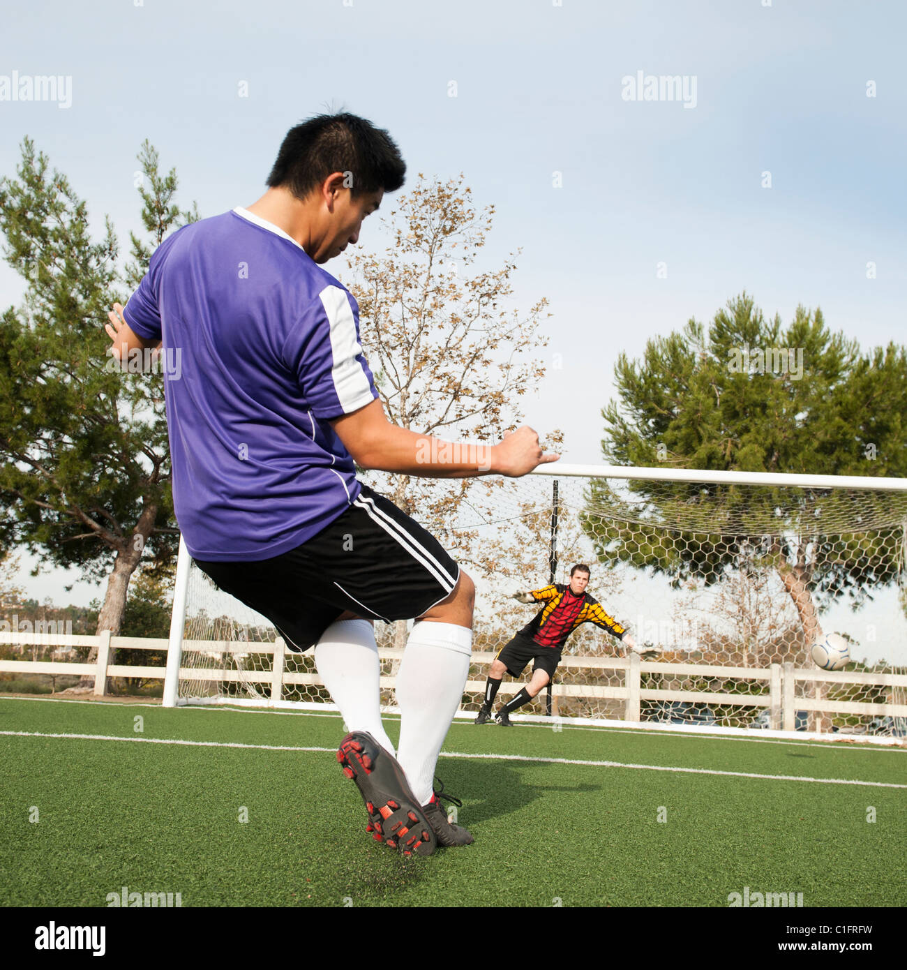Giocatore di calcio calci palla in obiettivo sul campo di calcio Foto Stock