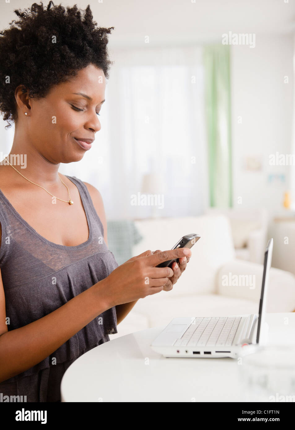 Donna nera di messaggistica di testo sul telefono cellulare Foto Stock