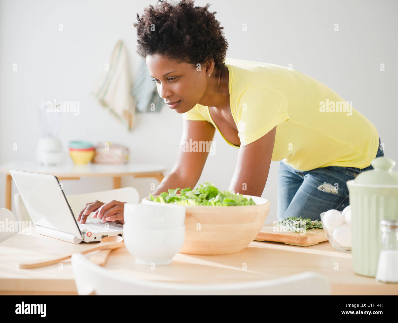 Nero donna utilizzando computer portatile sul tavolo da pranzo Foto Stock