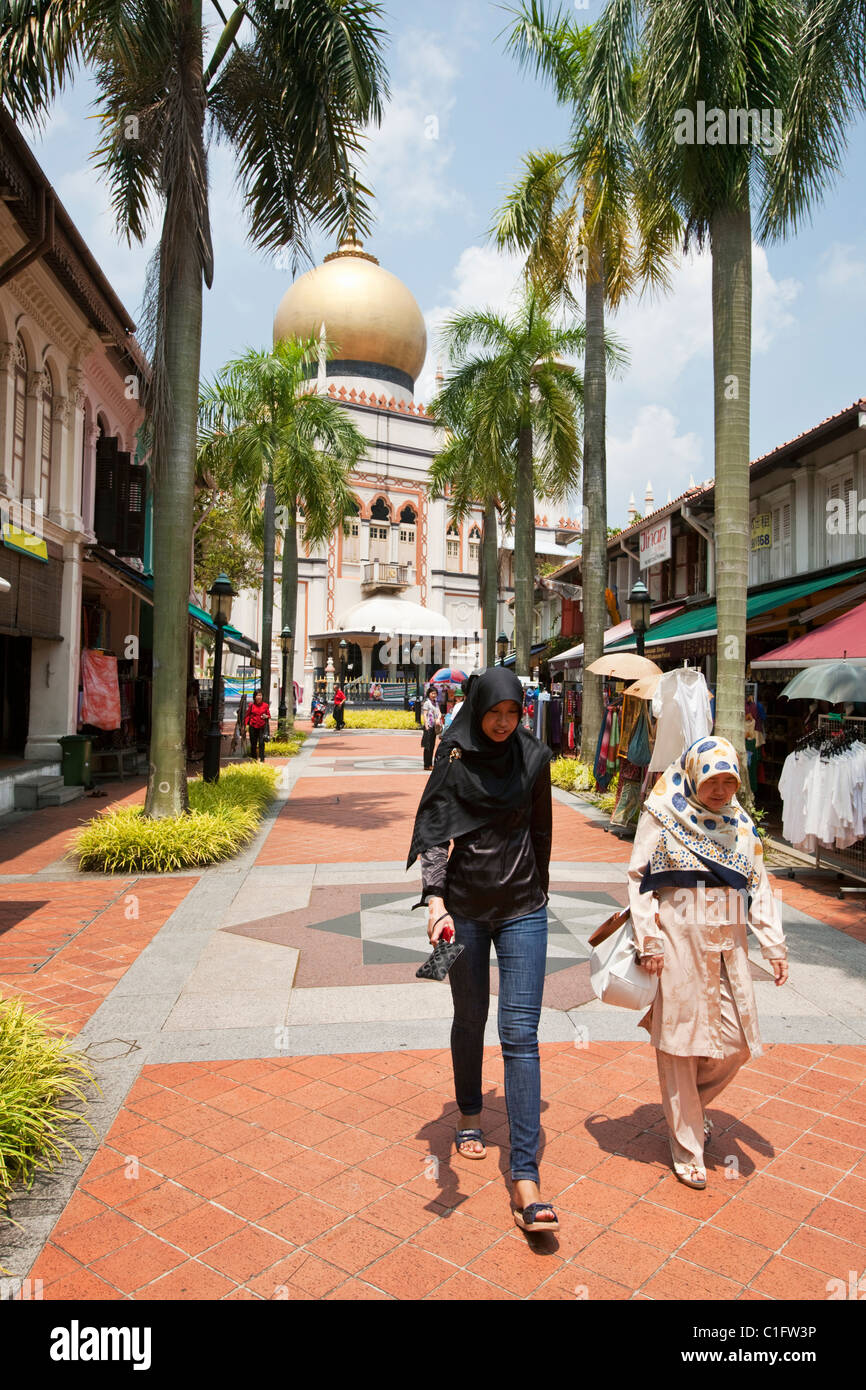 Le donne Malay camminando lungo Bussorah Street con la Moschea del Sultano in background. Quartiere arabo, Singapore Foto Stock