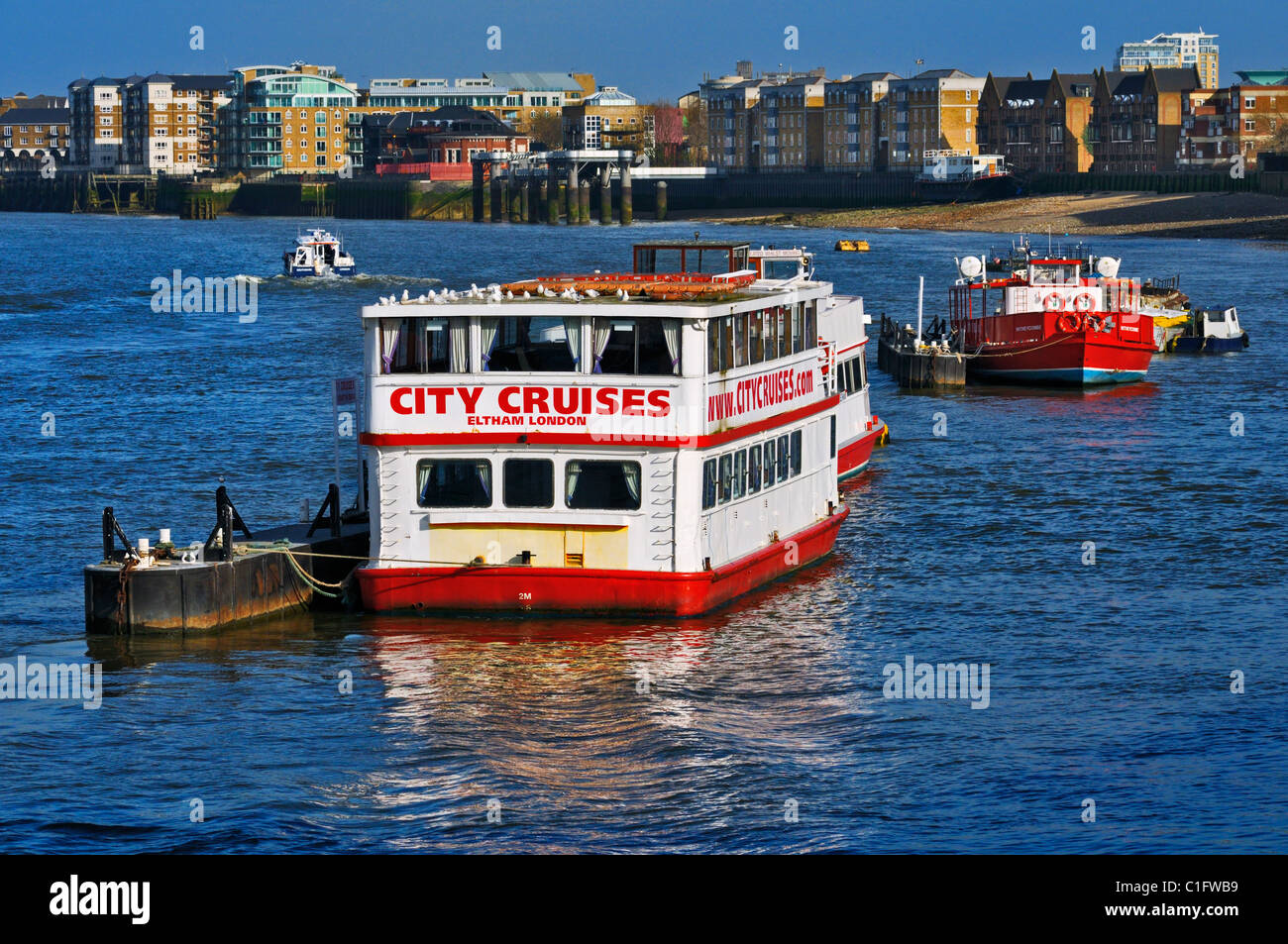 Crociera della Citta' riverboat M.T. Eltham ormeggiato sul fiume Tamigi con appartamenti moderni lungo le rive, London, Regno Unito Foto Stock