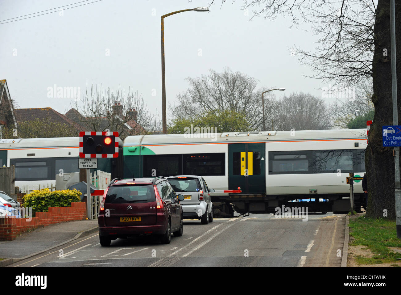 Incrocio ferroviario barriera con treno in viaggio passato a Road Horsham East Sussex Regno Unito Foto Stock