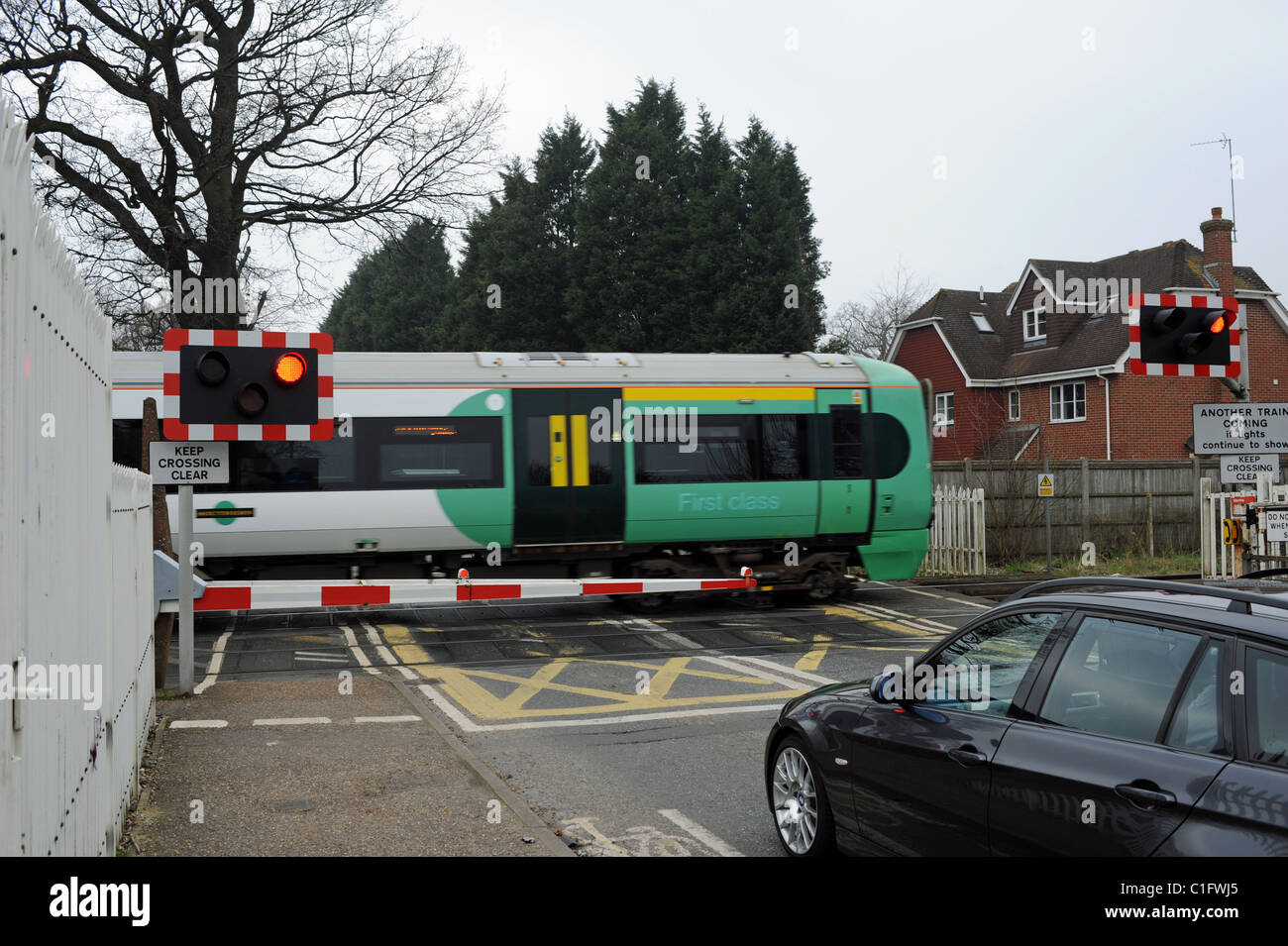 Incrocio ferroviario barriera con treno in viaggio passato a Road Horsham East Sussex Regno Unito Foto Stock