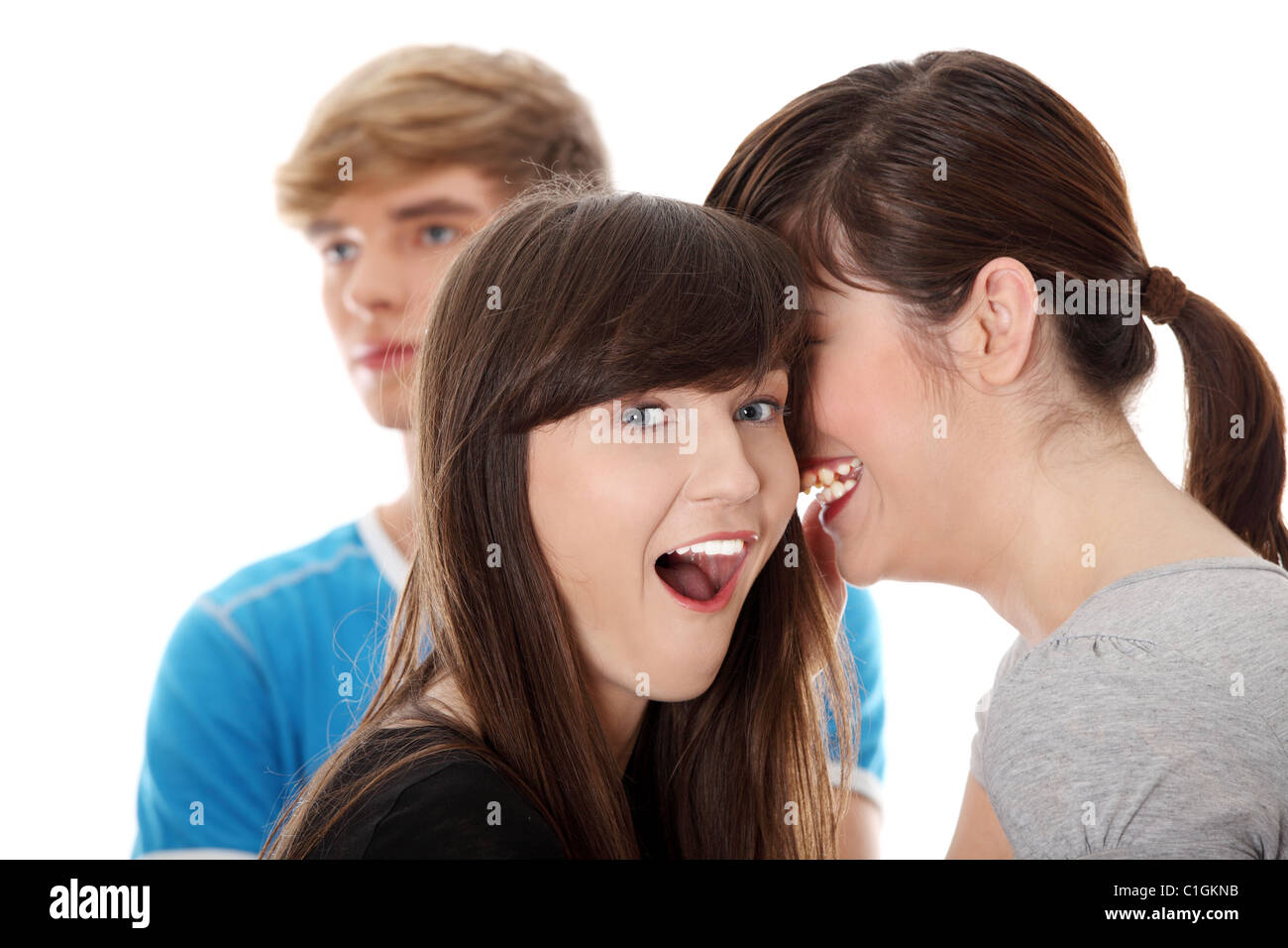Due ragazze parlano (gossip) circa il ragazzo, isolato su bianco Foto Stock