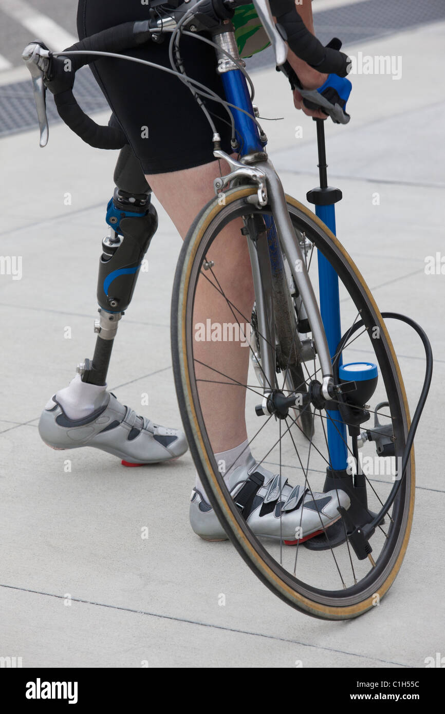 Donna con una gamba protesico pompando aria in una bicicletta Foto Stock