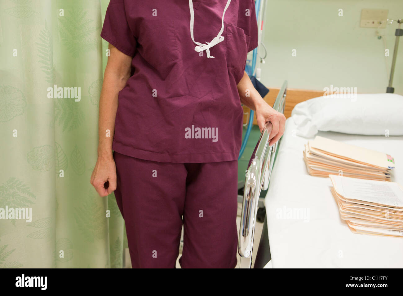 Infermiera femmina in piedi accanto a un posto letto in ospedale Foto Stock