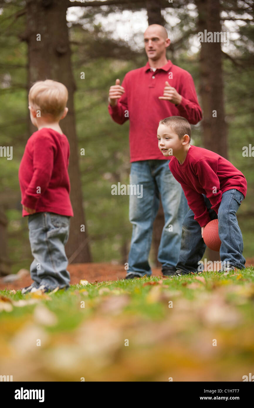 L'uomo firma la parola 'Play' in American Sign Language mentre gioca con i suoi figli in un parco Foto Stock