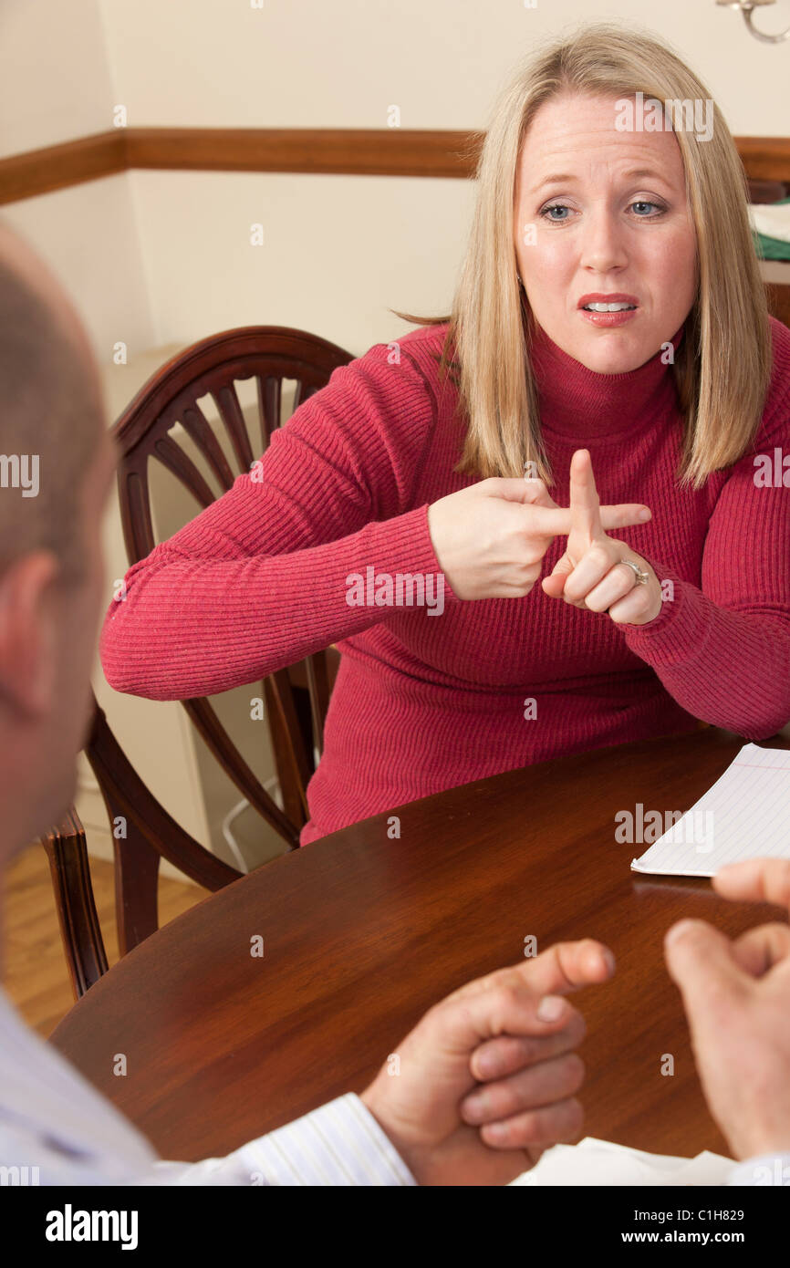 Donna firma la parola 'affitto' in American Sign Language durante la comunicazione con un uomo Foto Stock