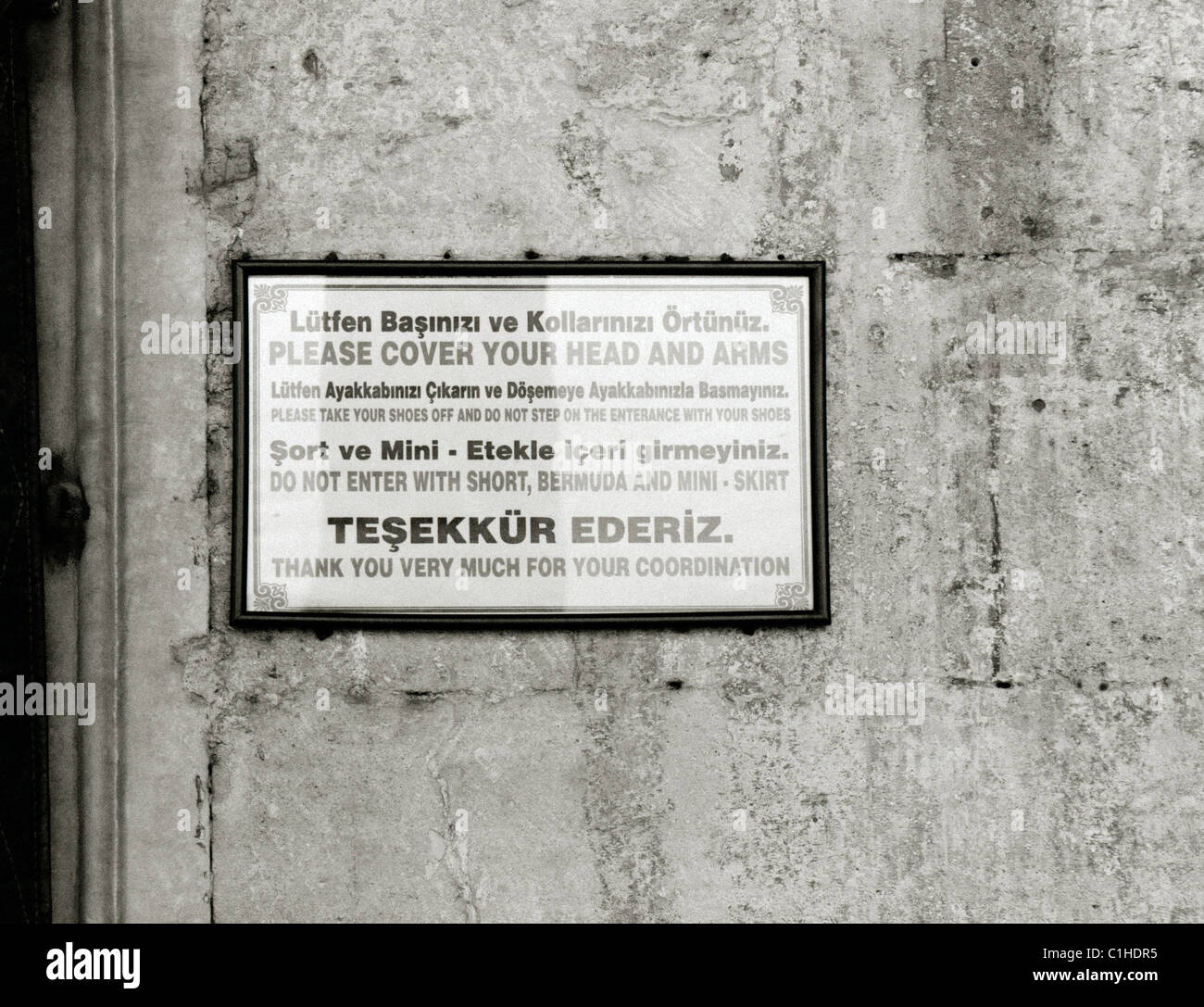 Fotografia di viaggio - un segno al di fuori della nuova moschea di Istanbul in Turchia nel Medio Oriente chiedendo ai visitatori di togliere le scarpe dopo aver immesso. Foto Stock