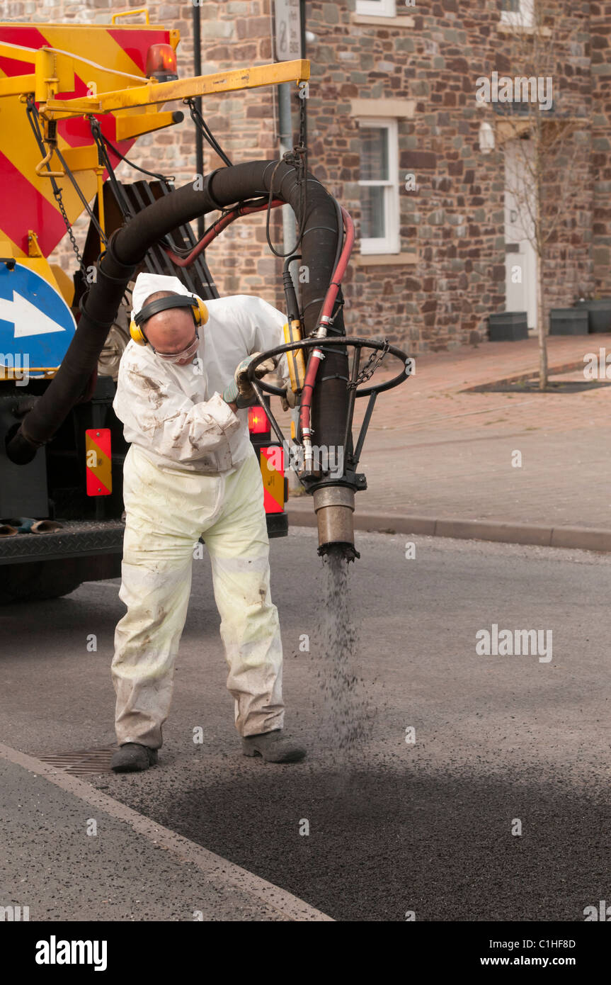 Un lavoratore di velocità di riparazione di buche in una strada con un a spruzzo ad alta pressione sistema blaster, REGNO UNITO Foto Stock