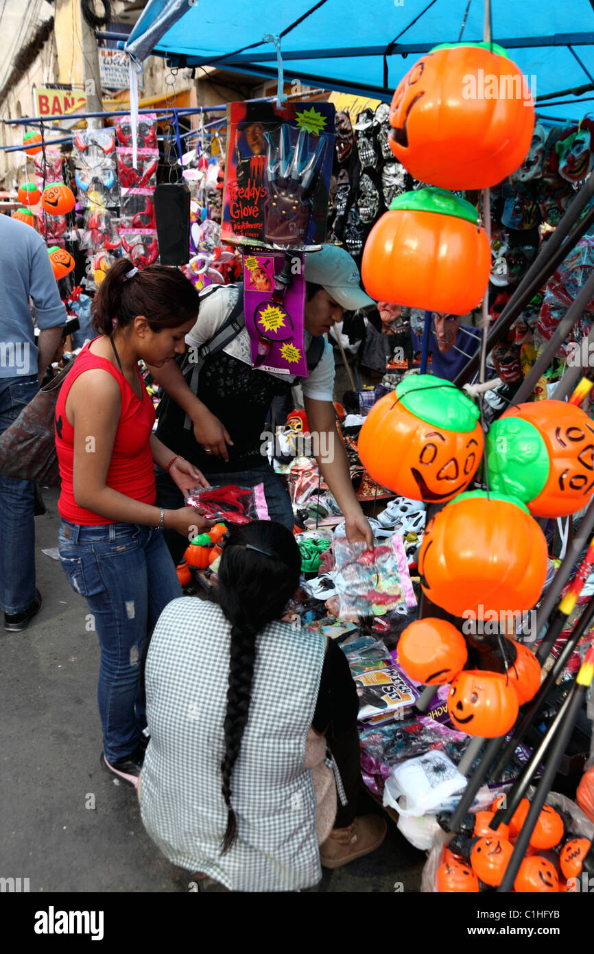 Giovane donna che acquista costumi per Halloween al mercato di strada, la Paz, Bolivia Foto Stock