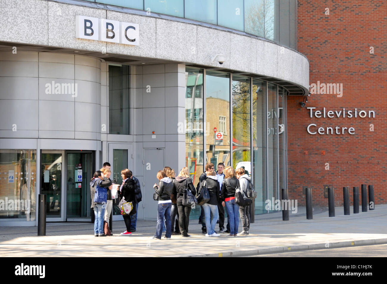 London street scene gruppo di persone che vivono al di fuori di ingresso alla BBC Television Centre edificio con sicurezza paracarri Città Bianca Londra Inghilterra REGNO UNITO Foto Stock