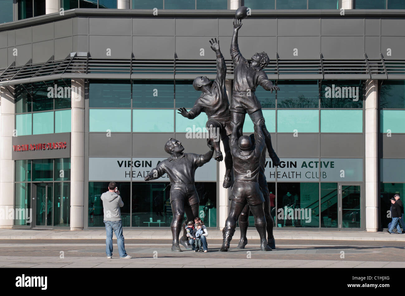 Una famiglia pongono in da di Gerald Laing scultura raffigurante un rugby line-out, al di fuori di Twickenham Rugby Stadium, Londra, Regno Unito. Foto Stock