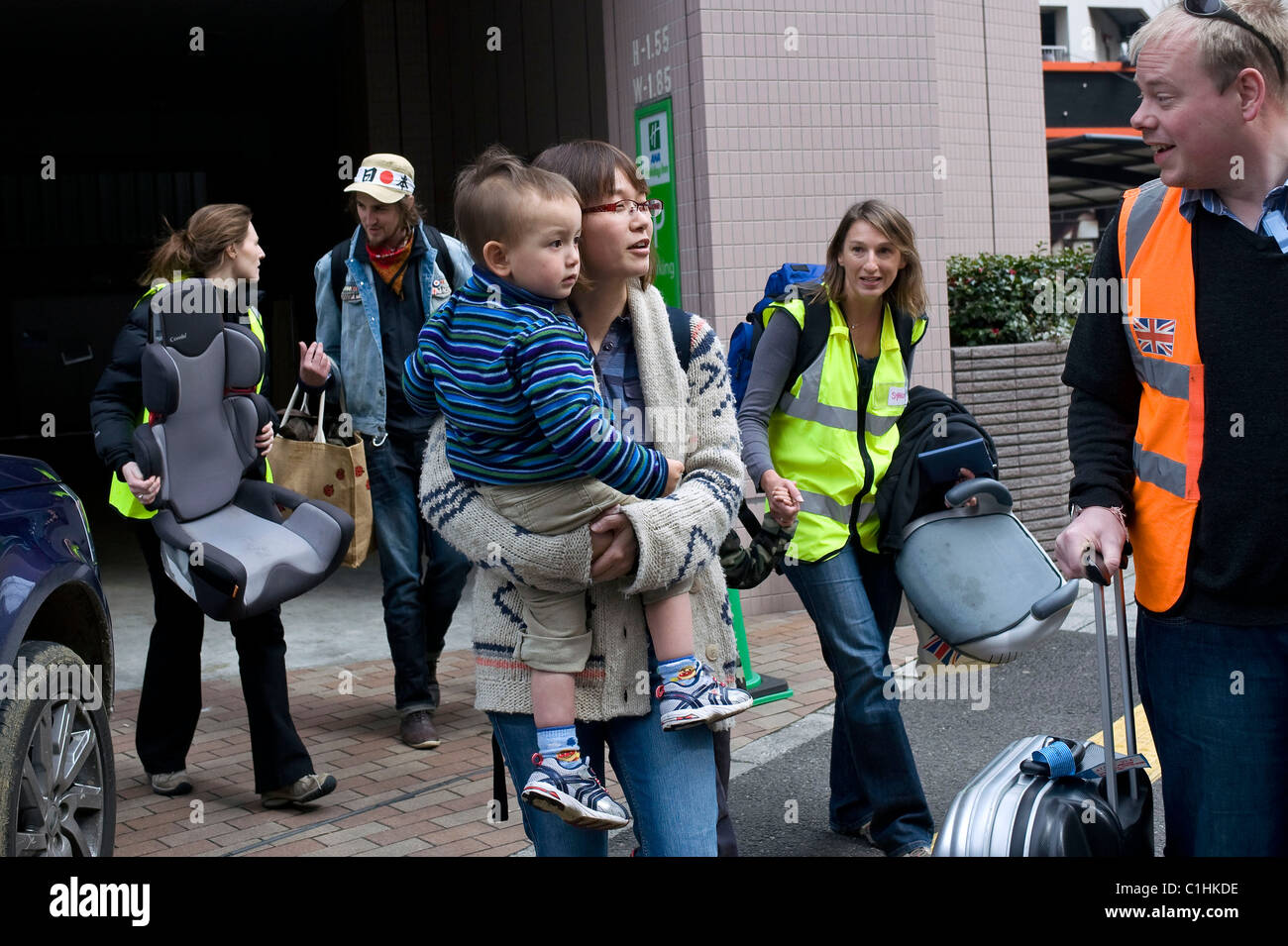 Alastair Dixon (2R), 30 da Cambridgeshire e la sua famiglia attendere l'ultimo bus out di Sendai, Giappone Foto Stock