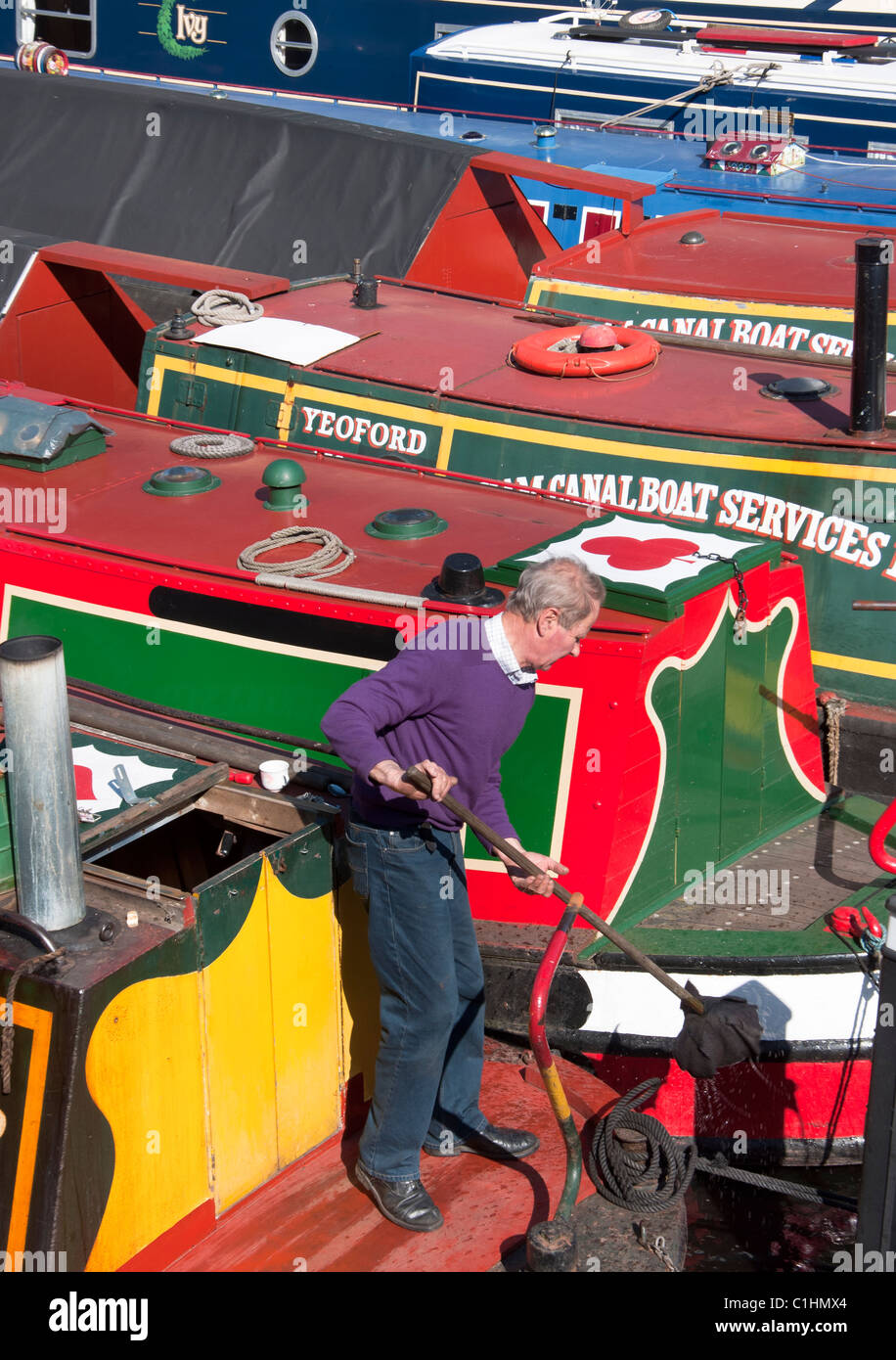 Un uomo locale su una delle colorate barche a lungo sul Gas Street Basin nella zona centrale di Birmingham, Inghilterra. Foto Stock