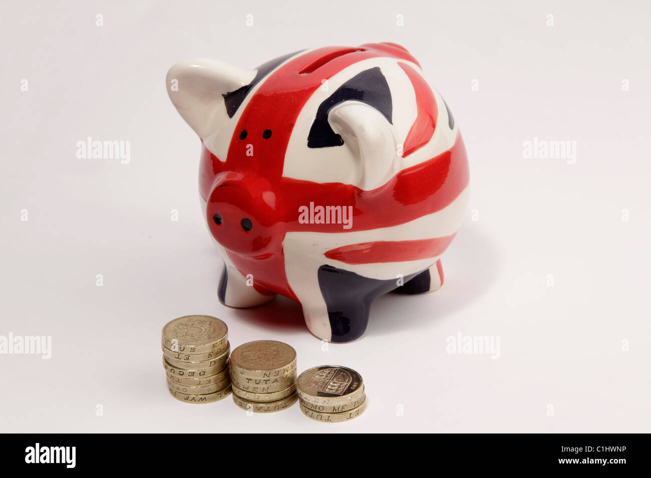 Il denaro di maiale scatola dipinta con un REGNO UNITO "Union Jack' bandiera e alcuni inglesi una sterlina monete poste nella parte anteriore di essa. Foto Stock
