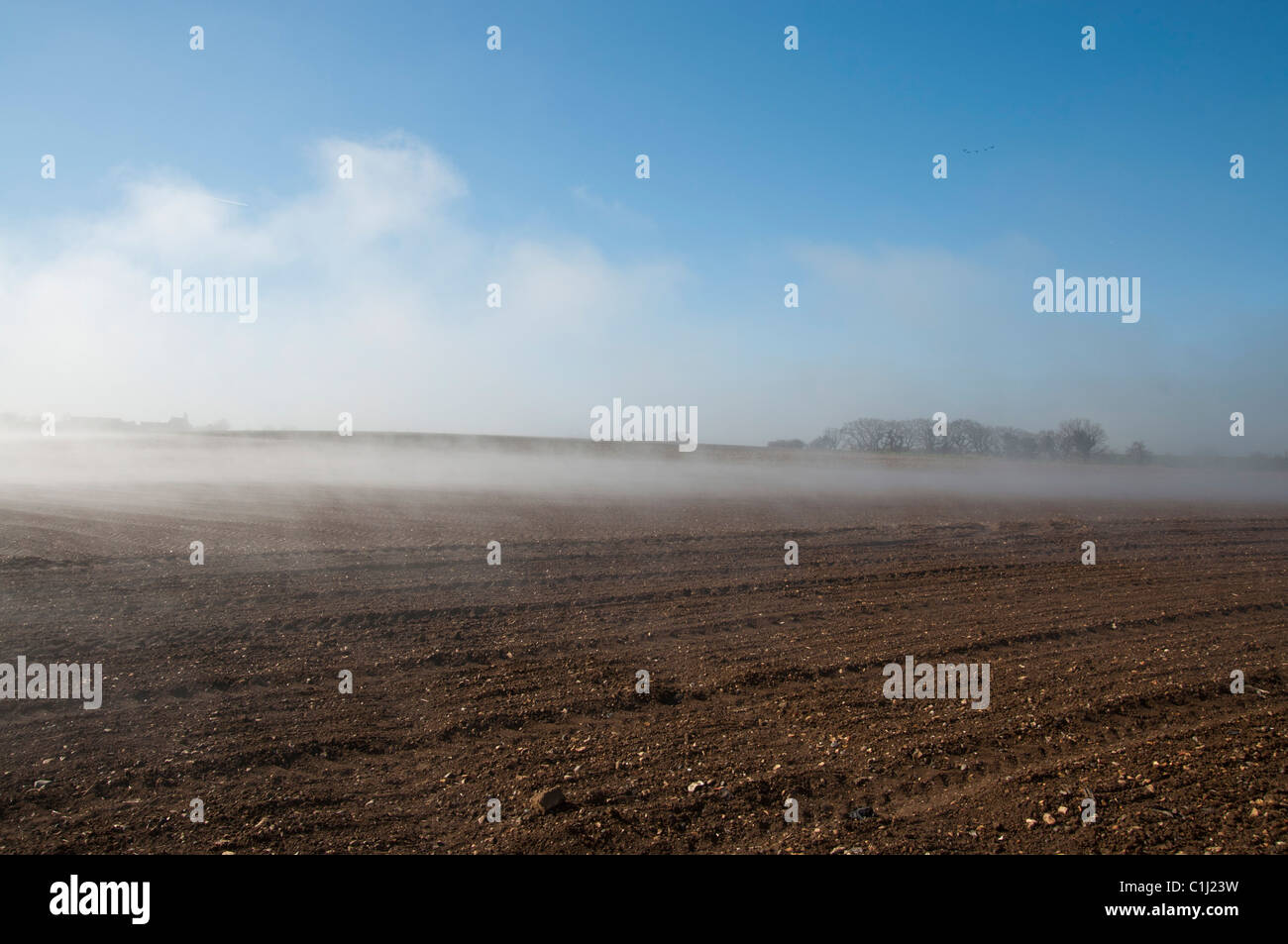 La nebbia che salgono dal campo la mattina presto luminoso caldo sole brucia fuori l'acqua dal campo arato Foto Stock