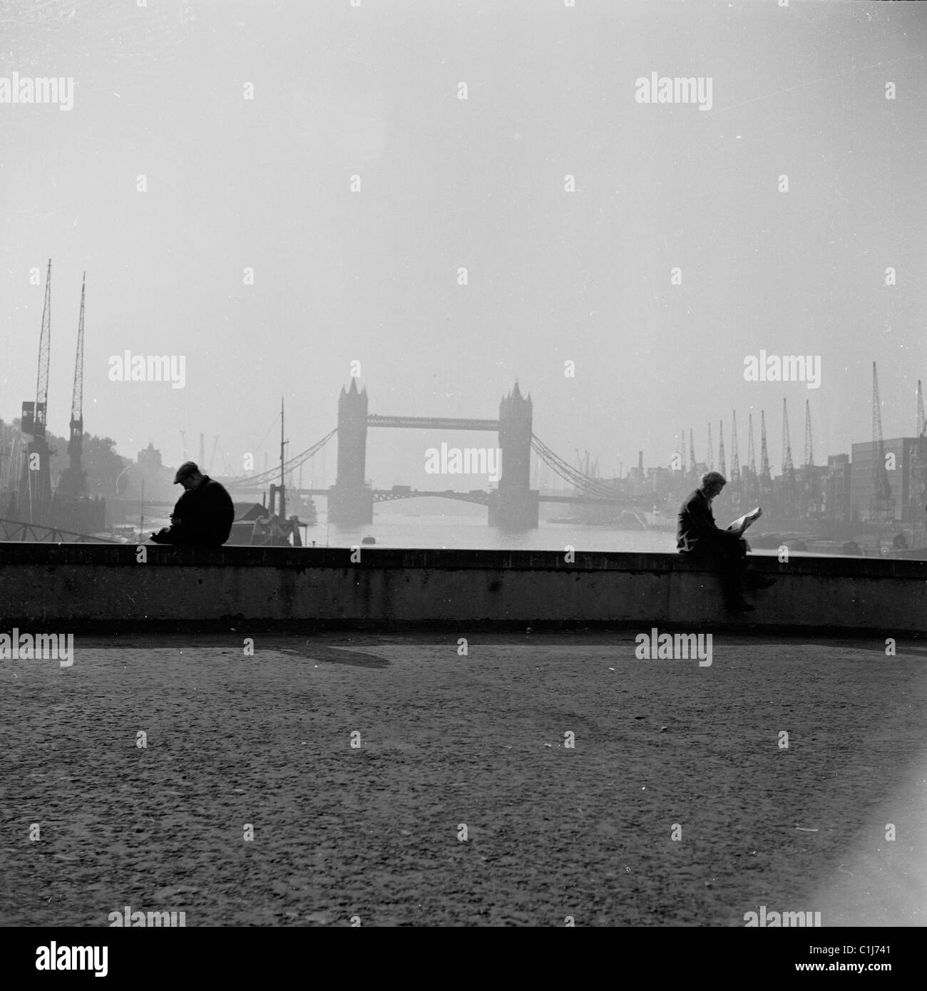 Anni '1950, due uomini seduti su un muro basso sul New London Bridge vicino al Tamigi in questa foto di J Allan Cash. Tower Bridge in lontananza. Foto Stock