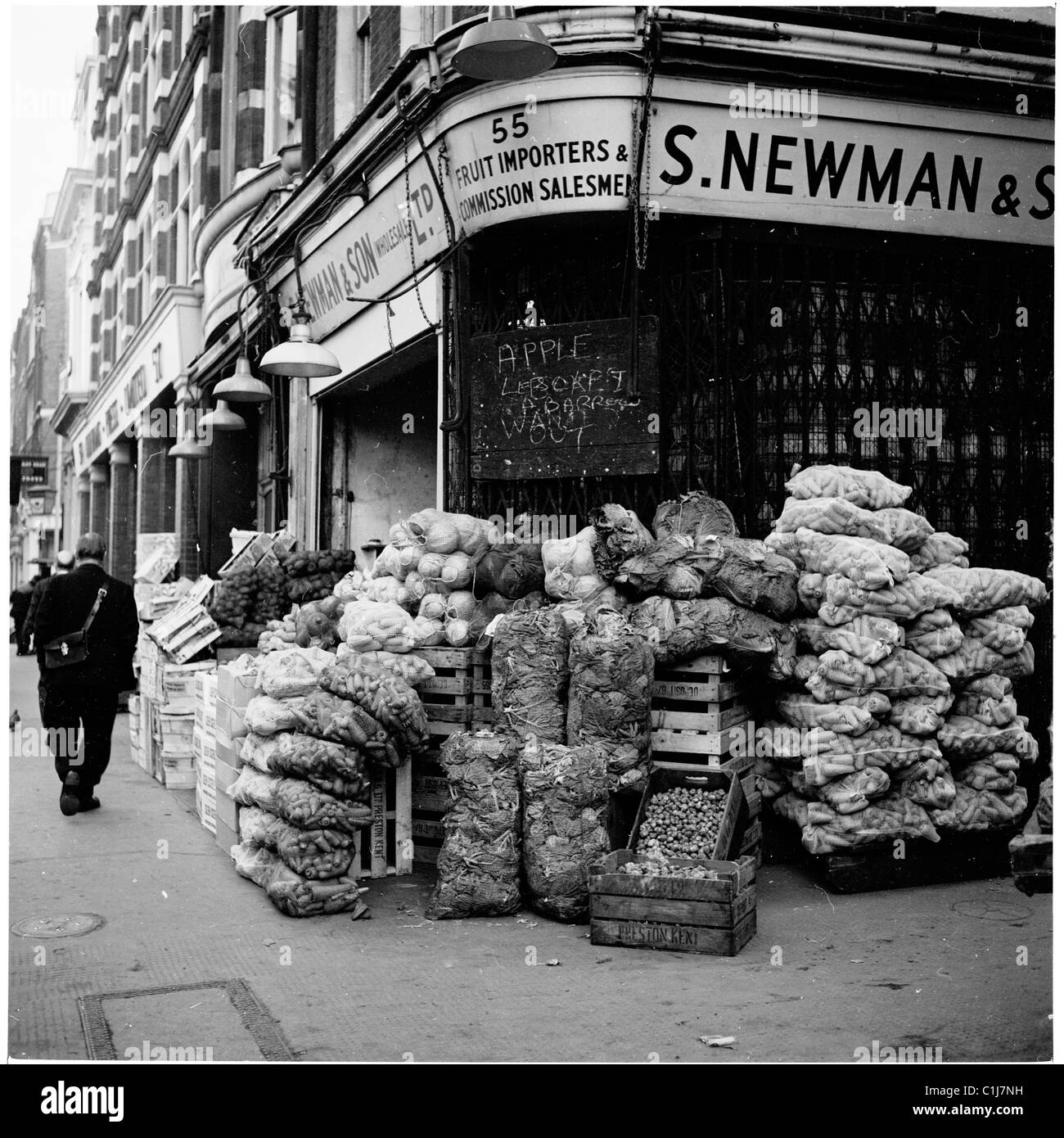Anni '1950, sacchi e casse di frutta e verdura sul marciapiede all'esterno di importatori e grossisti di frutta, S. Newman & Sons, Londra, Inghilterra. Foto Stock
