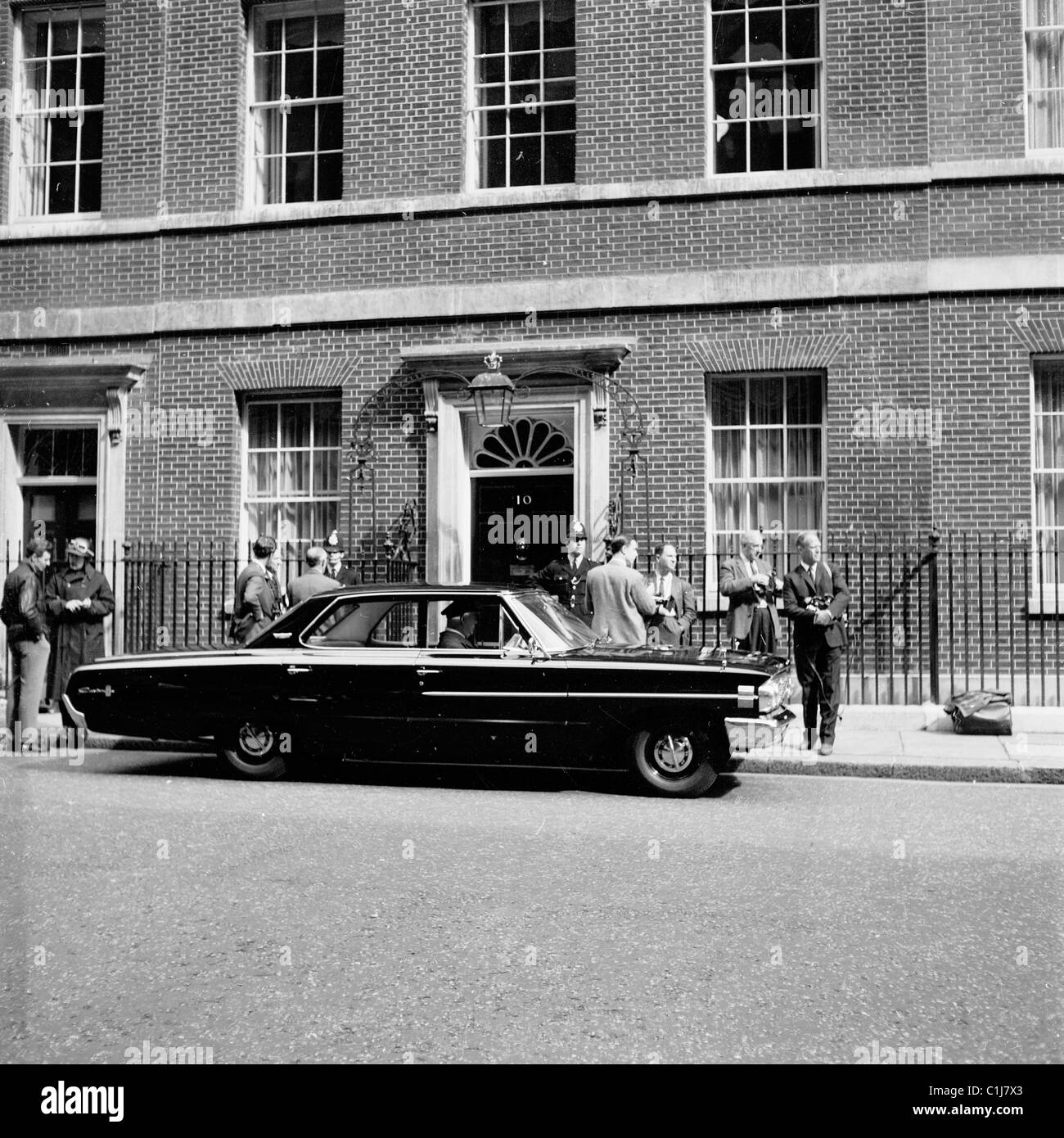 Londra,1960s, un conducente di una vettura americana attende come i giornalisti e i fotografi si raccolgono al di fuori n. 10 di Downing Street, la casa del Primo Ministro del Regno Unito. Foto Stock