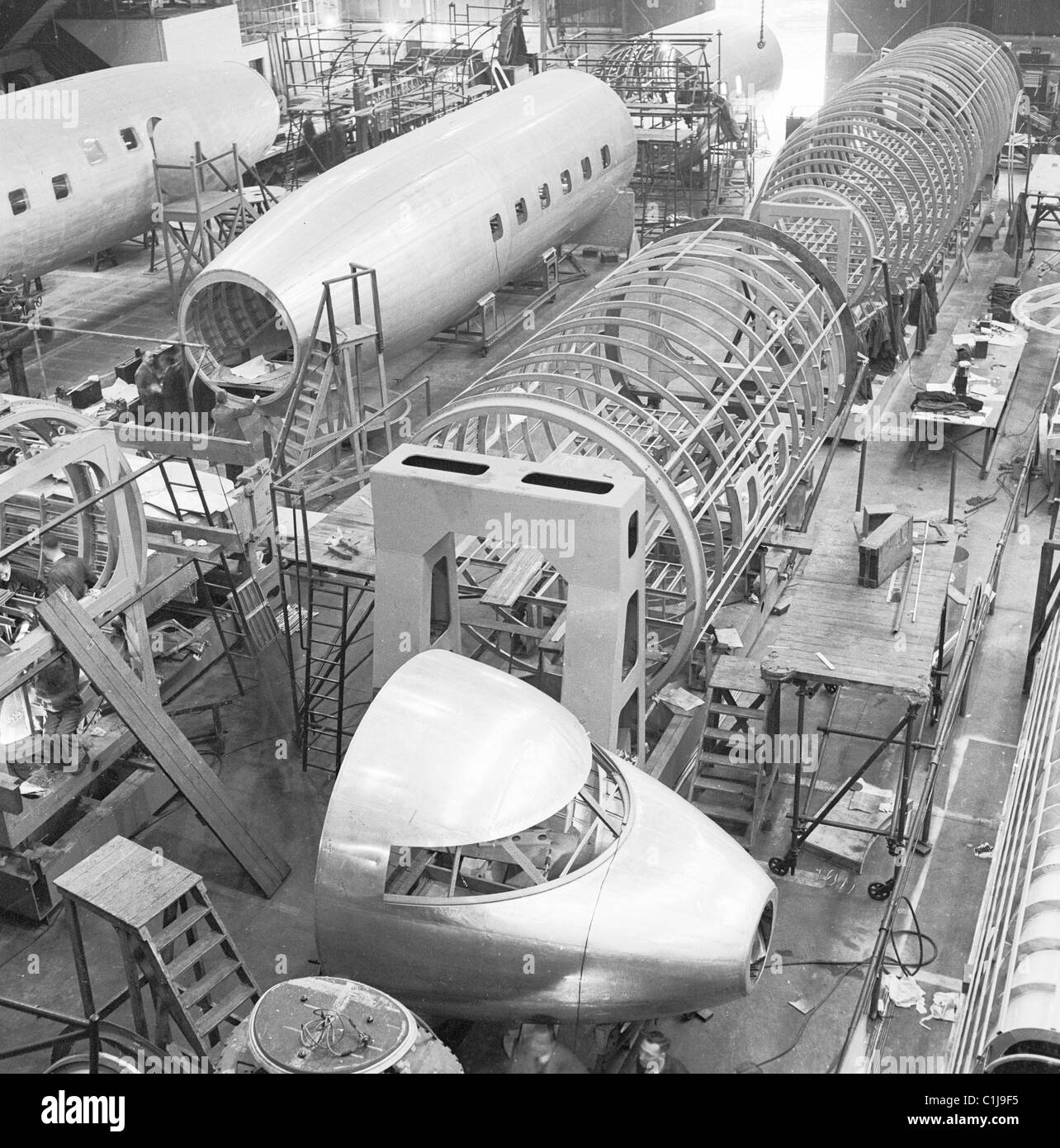 Anni '1950, storici aeroplani civili in costruzione in un grande hangar, che mostra le sezioni di conchiglie, scafi e cabina di pilotaggio, Londra, Inghilterra, Regno Unito. Foto Stock