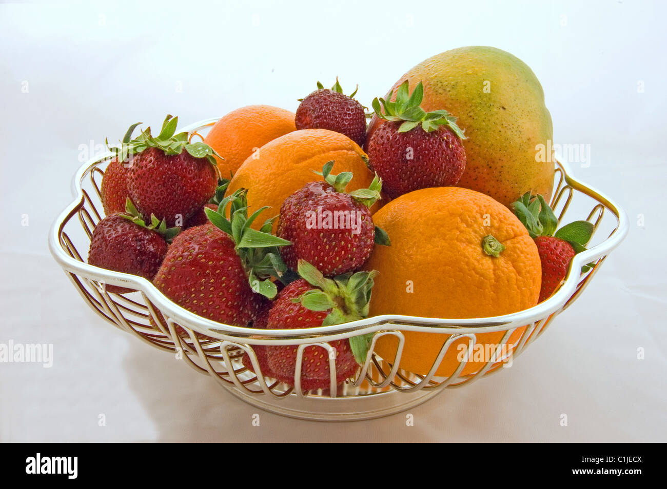 Si tratta di una vita ancora di un piatto d'argento di mango, le fragole e le arance per una bellissima foto di frutta fresca. Prese su una luce Foto Stock