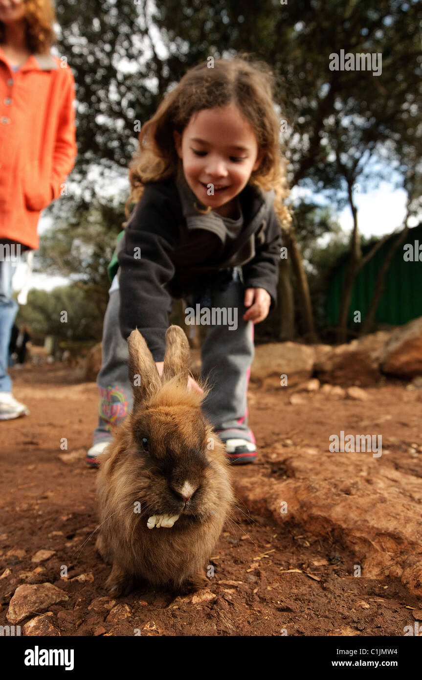 Bambino con un coniglio in un angolo delle carezze in un zoo per bambini Foto Stock