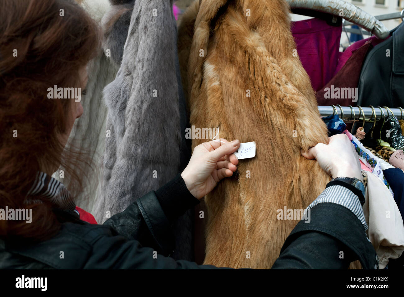 Donna visualizzazione prezzo di seconda mano pelliccia sul mercato in stallo Foto Stock