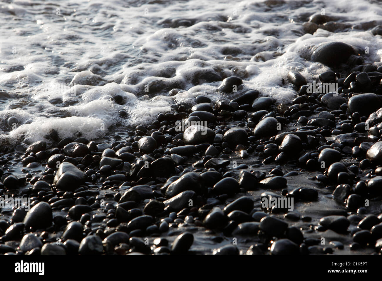 Spiaggia nera pietre surf Foto Stock