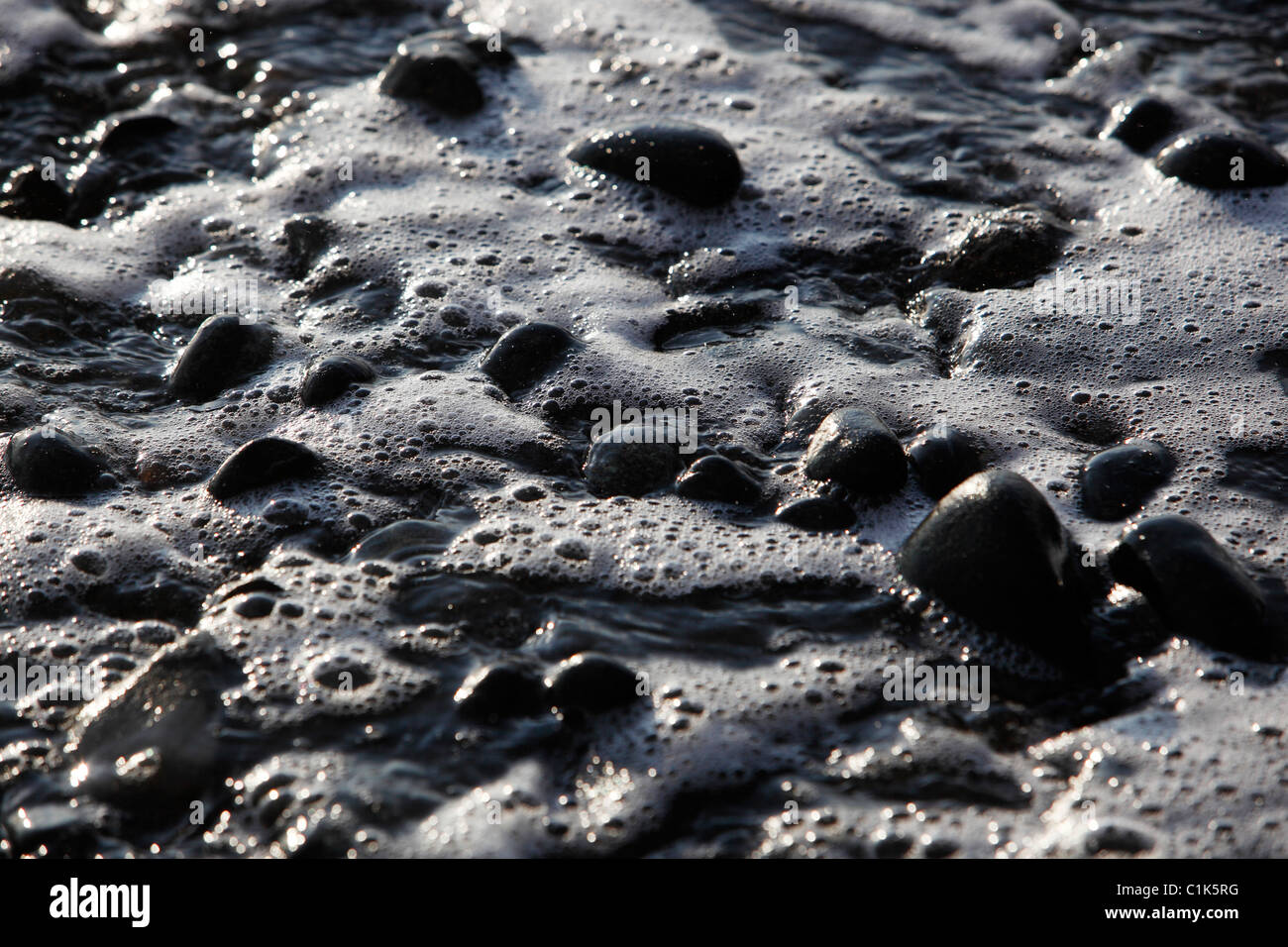 Spiaggia nera pietre surf Foto Stock